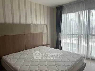 Modern bedroom with large window and city view, featuring a stylish bed and elegant curtains.