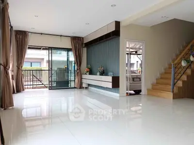Spacious modern living room with large windows and staircase