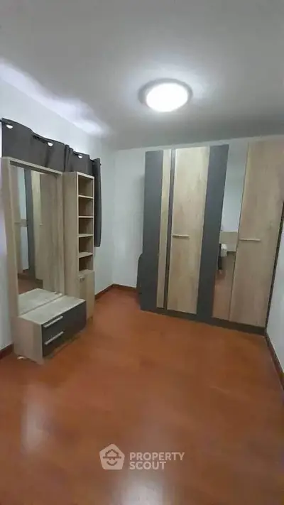 Spacious bedroom with modern wardrobe and wooden flooring