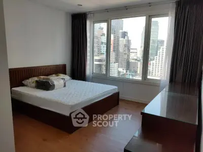 Spacious bedroom with city view and modern furnishings in high-rise apartment.