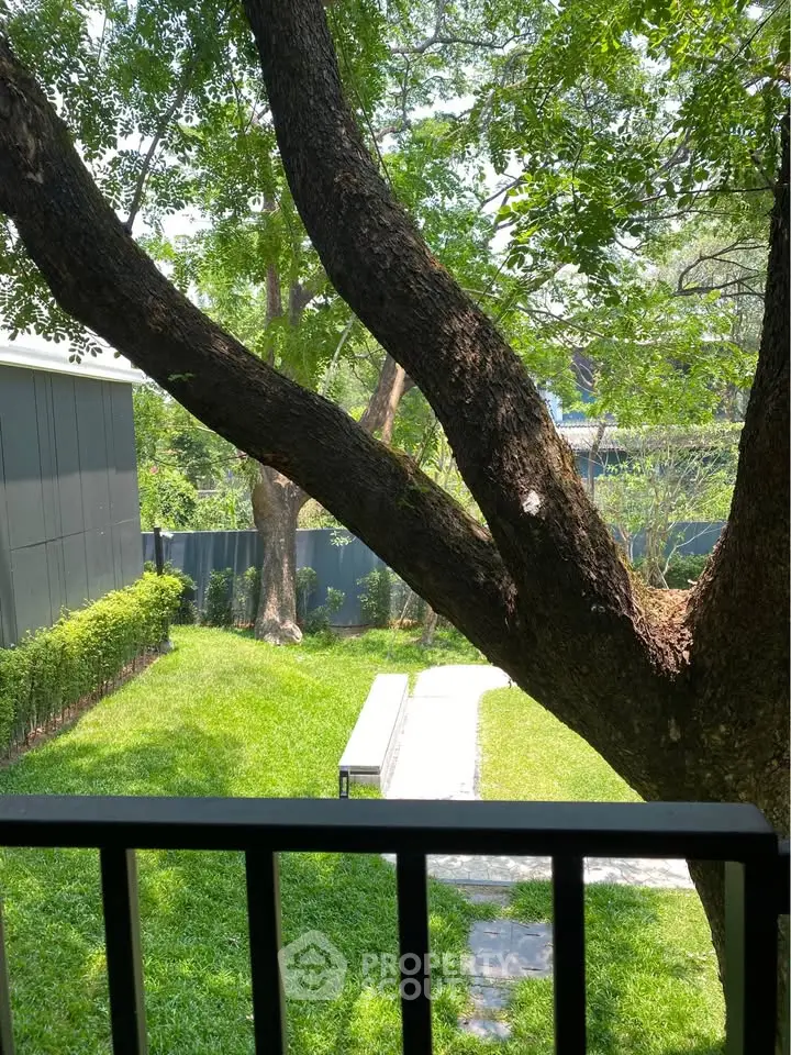 Charming garden view with lush greenery and mature trees from a balcony, perfect for relaxation.