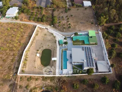 Aerial view of a luxurious estate with a pool, solar panels, and expansive grounds.
