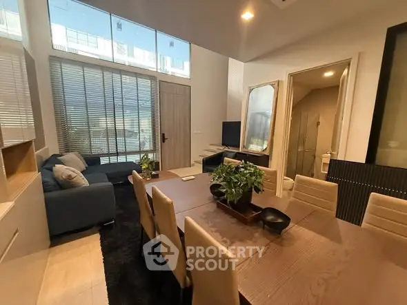 Modern living and dining area with large windows and stylish decor