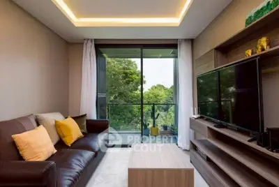 Modern living room with large TV, cozy sofa, and balcony view of lush greenery.