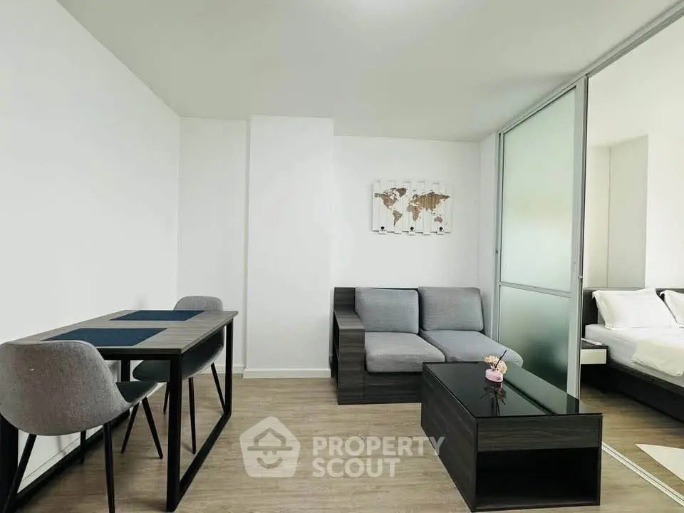 Modern living room with sleek furniture and adjacent bedroom in a stylish apartment.