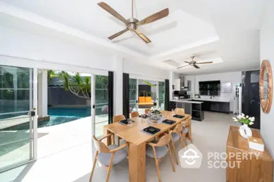 Spacious open-plan living area with modern kitchen, large dining table, and seamless indoor-outdoor flow to a private pool area, perfect for entertaining.