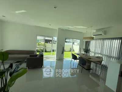 Spacious modern living room with dining area and garden view, featuring sleek furniture and abundant natural light.