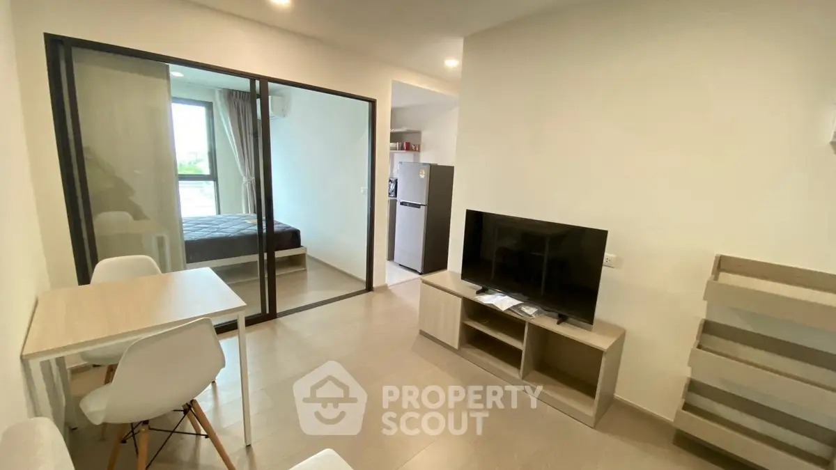 Modern living room with glass partition, TV unit, and dining area in a stylish apartment.