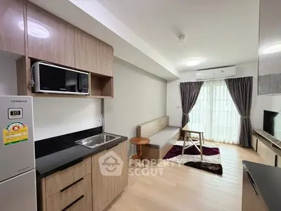 Modern apartment living room with kitchenette, featuring sleek cabinets and natural light.