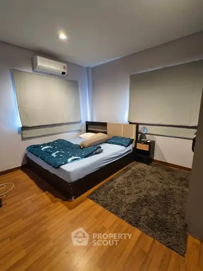 Cozy bedroom with wooden flooring and modern air conditioning unit, perfect for relaxation.