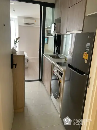 Modern compact kitchen with washing machine and fridge in stylish apartment.