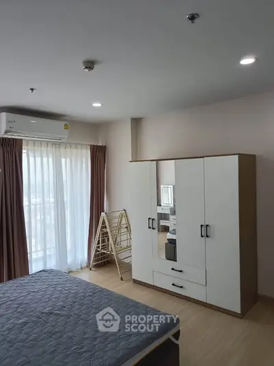 Spacious bedroom with modern wardrobe and natural light in a stylish apartment.