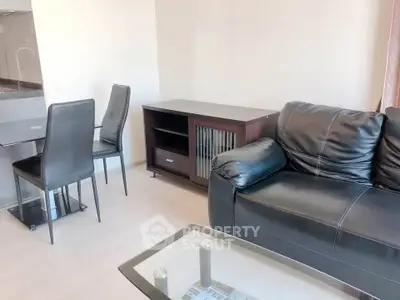 Modern living room with sleek black leather sofa and dining area in open layout apartment.