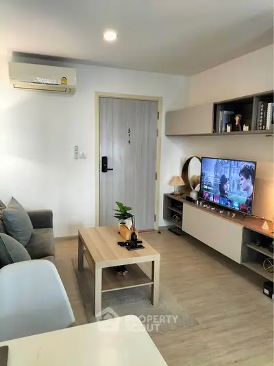 Modern living room with cozy sofa, wall-mounted TV, and stylish decor in a contemporary apartment.