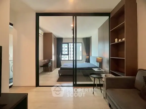 Modern bedroom with glass partition and cozy living area in stylish apartment.