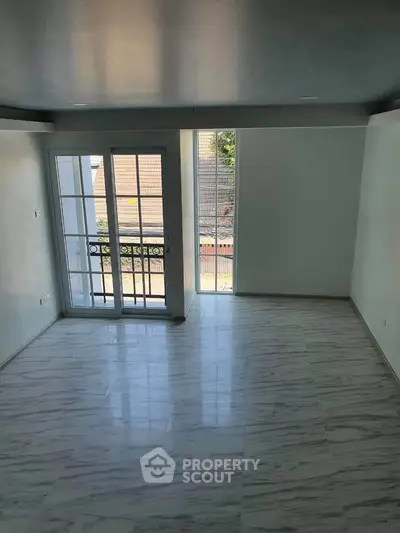 Spacious room with elegant flooring and large windows offering natural light and a charming view.