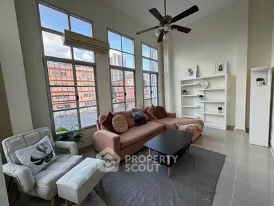 Spacious living room with high ceilings and large windows offering city views.