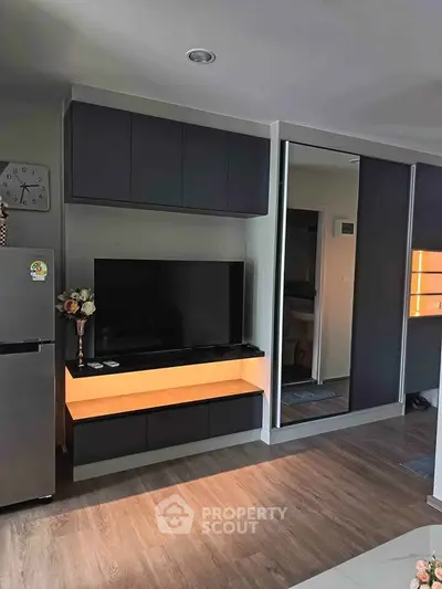 Modern living room with sleek TV unit and mirrored wardrobe, featuring elegant wood flooring.