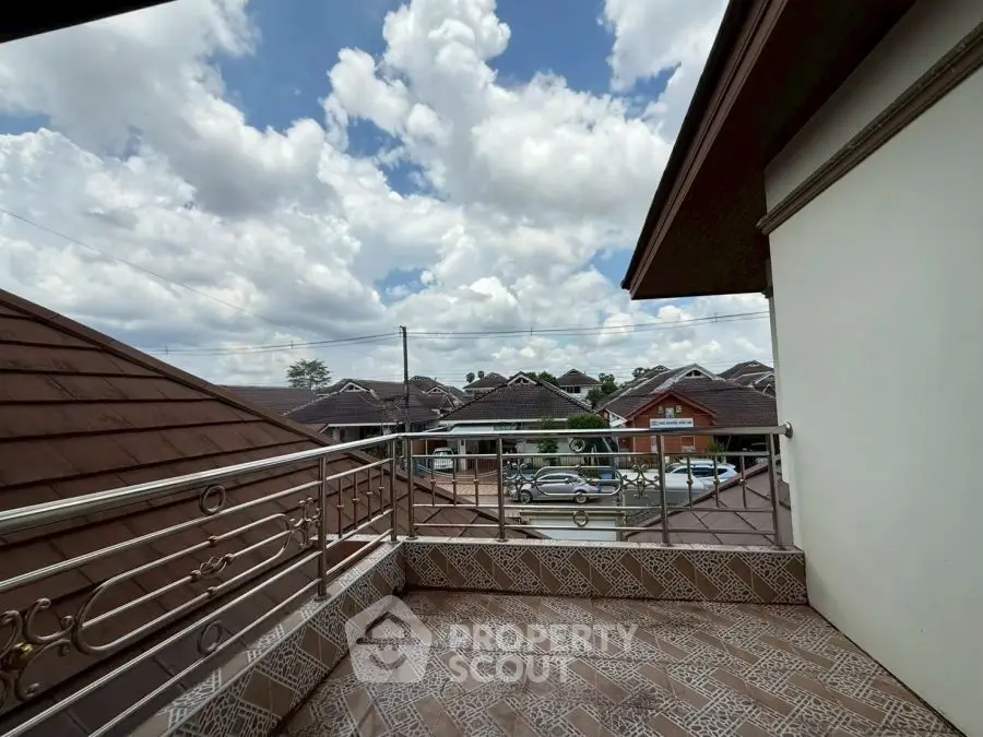 Charming balcony with scenic rooftop views and ornate railing under a bright sky.