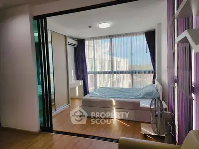 Modern bedroom with large windows and wooden flooring, featuring a comfortable bed and ample natural light.