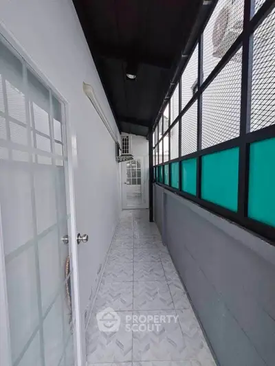 Narrow balcony with tiled flooring and glass doors in modern apartment