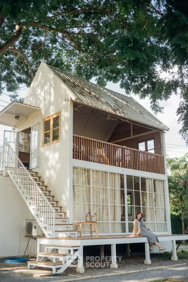 Charming two-story house with spacious balcony and lush surroundings, perfect for serene living.