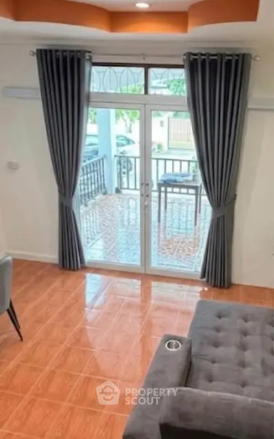Spacious living room with elegant curtains and glass doors leading to a tiled balcony.