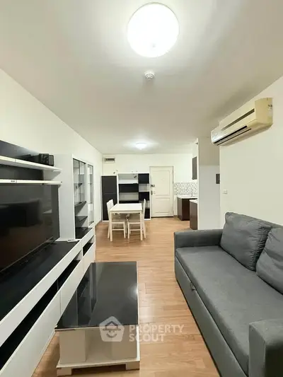 Modern living room with sleek furniture and open layout, featuring a cozy sofa and stylish entertainment center.