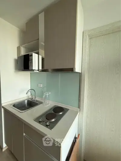 Compact modern kitchen with sleek cabinetry and built-in appliances in a cozy apartment.