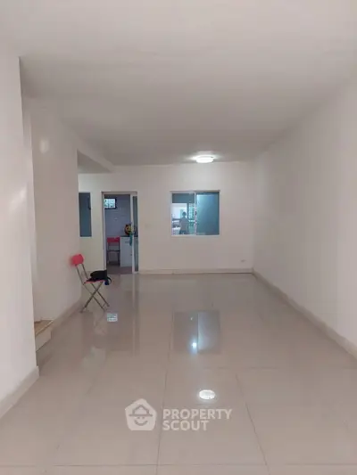 Spacious empty living room with tiled flooring and minimalistic design.