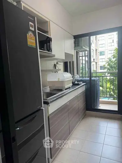 Modern kitchen with sleek appliances and balcony view in urban apartment