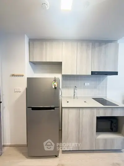 Modern kitchen with sleek cabinetry and stainless steel fridge in a compact layout.