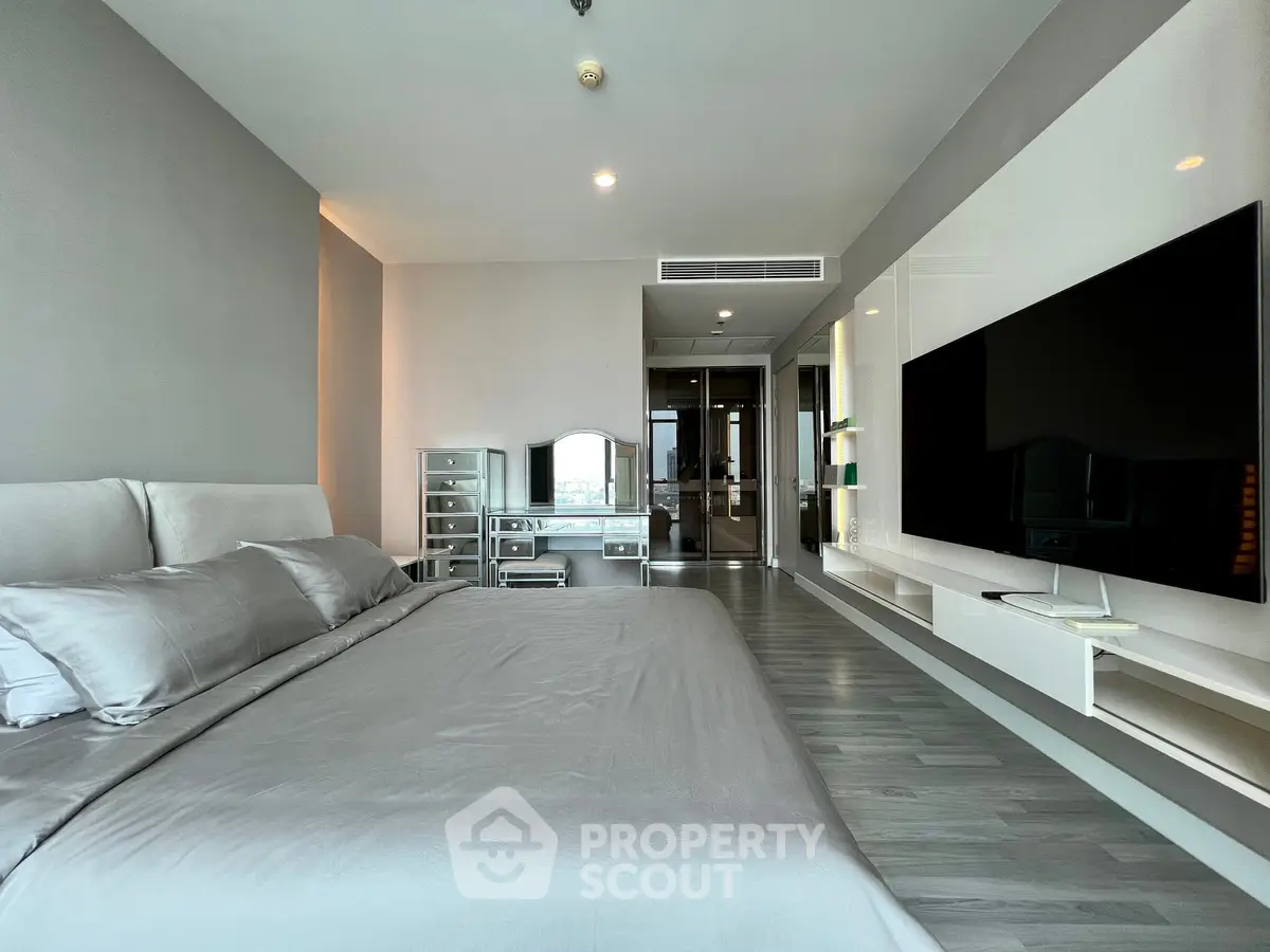Luxurious modern bedroom with sleek design and large TV, perfect for relaxation and entertainment.