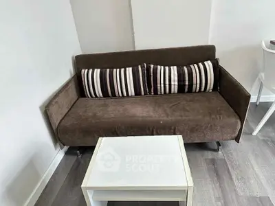 Cozy living room with modern brown sofa and white coffee table on stylish flooring.