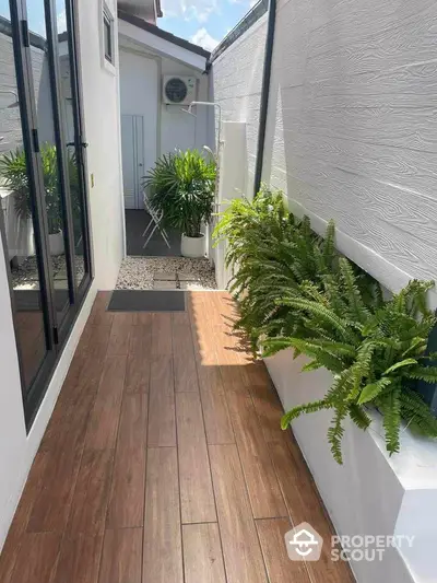 Charming narrow outdoor corridor with wooden flooring and lush greenery