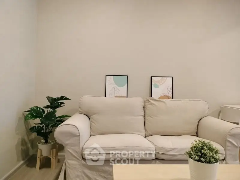 Cozy living room with beige sofa and decorative plants, perfect for relaxation.