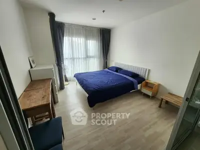 Spacious bedroom with modern furnishings and large window for natural light.