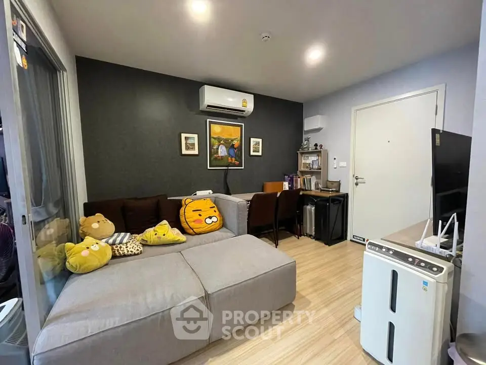 Cozy living room with modern decor and air conditioning, featuring a comfortable sofa and stylish artwork.