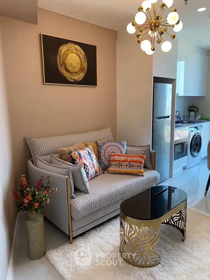 Stylish living room with modern decor, cozy sofa, chic coffee table, and open kitchen featuring appliances.
