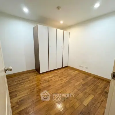 Spacious bedroom with wooden flooring and a large wardrobe, perfect for modern living.