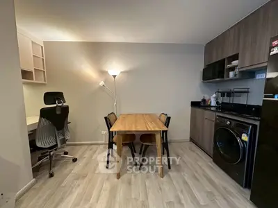 Modern apartment interior with dining table, study area, and kitchen appliances.