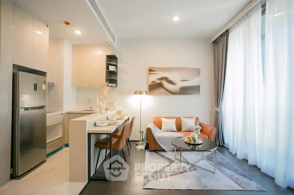 Modern open-layout living room with kitchen, featuring stylish decor and natural light.