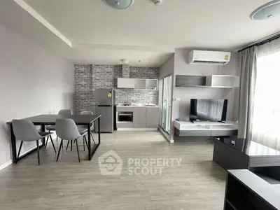 Modern open-plan living room with sleek kitchen and dining area, featuring stylish furniture and natural light.