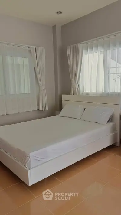 Bright and airy bedroom with modern white bed and large windows.