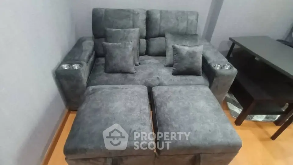 Modern living room with plush gray sofa and matching ottomans, perfect for relaxation.