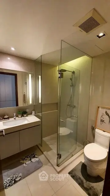 Modern bathroom with glass shower and sleek vanity in upscale apartment.