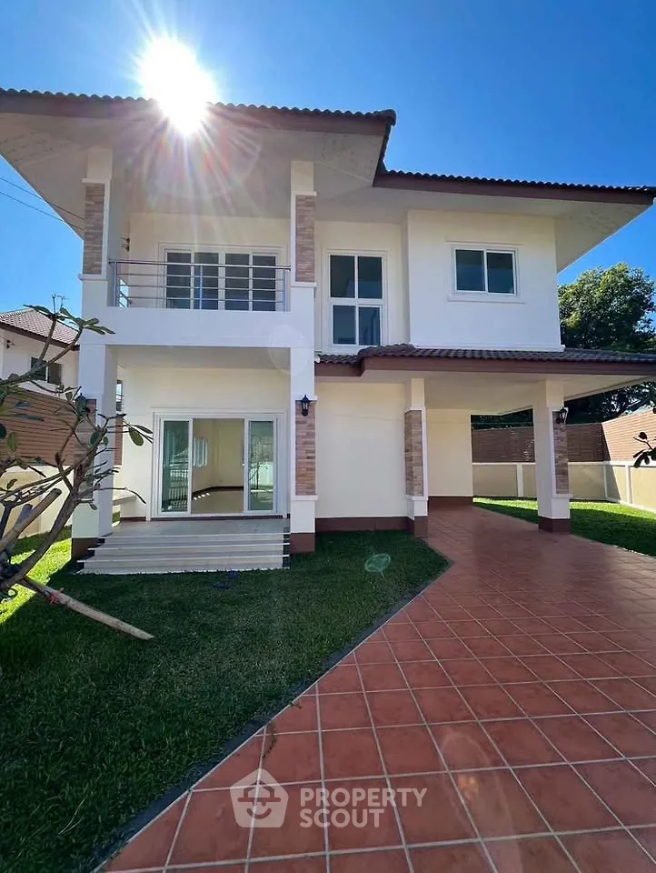 Stunning two-story house with spacious driveway and lush green lawn under a clear blue sky.