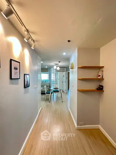 Stylish apartment hallway leading to a modern living area with sleek wooden flooring and contemporary decor.