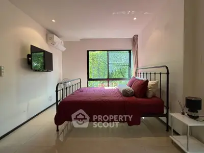 Spacious bedroom with modern decor and large window offering lush green views.