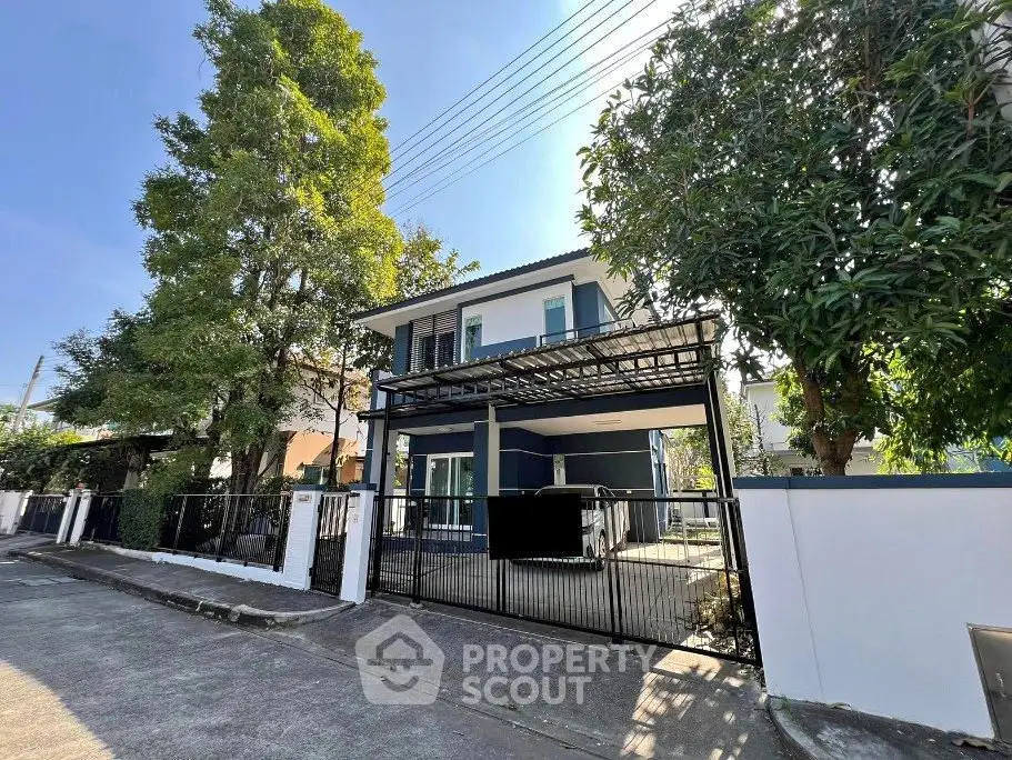 Charming two-story house with gated entrance and lush greenery